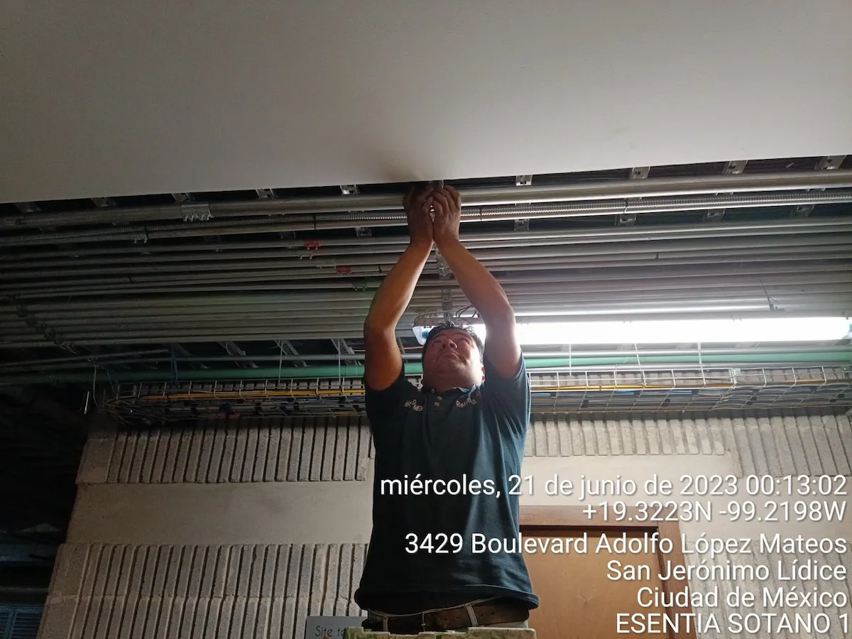 Técnico trabajando en canalización de techo junto a letrero de Site Telefónico en Sótano 1